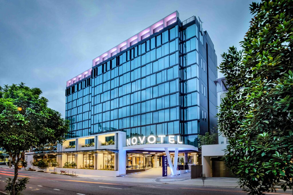 Exterior view of Novotel Brisbane South Bank hotel at dusk, with illuminated entrance and modern glass façade in Brisbane, Australia.